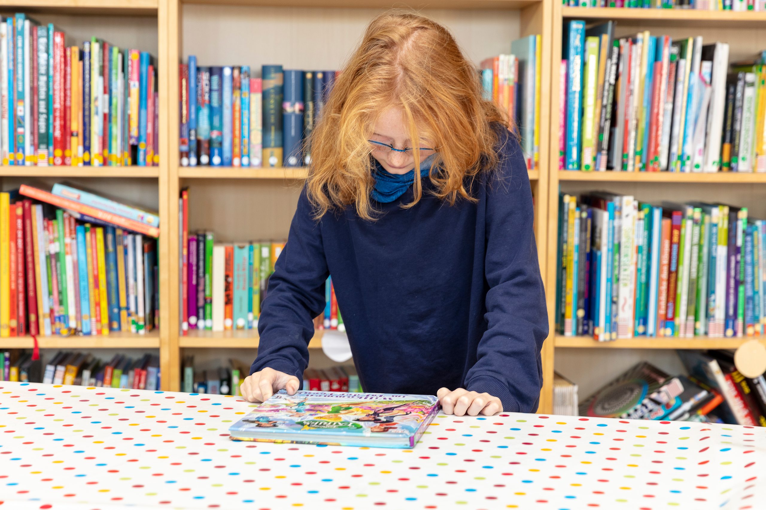 Anne sieht sich das Cover des Buches, welches vor ihr auf dem Tisch liegt, aufmerksam an.