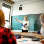 Wo finde ich Hilfe - Lehrerin unterrichtet mit Mund-Nasen-Maske