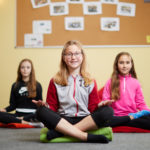 Schülerinnen praktizieren Yoga