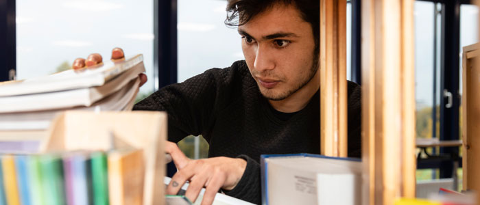 Schüler vor Bücherregel in Schulbibliothek