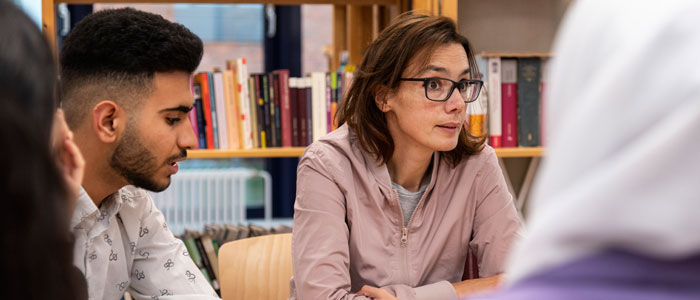 Lehrerin mit Schülerinnen und Schülern in der Schulbibliothek