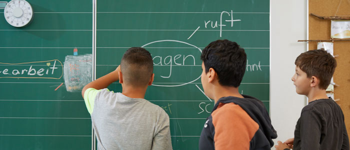 Drei Schüler schreiben an die Tafel