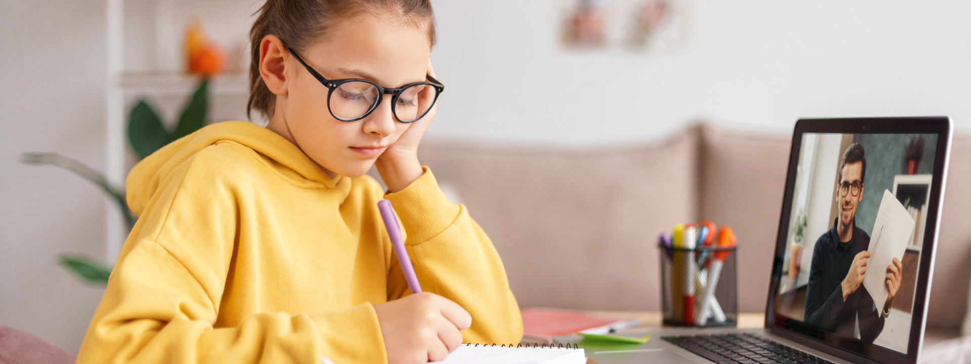 Mädchen beim Schulunterricht Zuhause mit Laptop und Schreibuntensilien