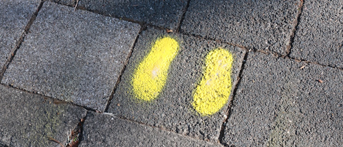 Gelbe Fußabdruckmarkierung auf einem Bürgersteig