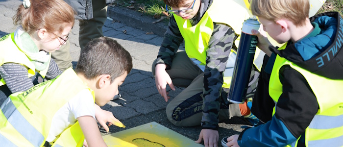 Kinder tragen mit gelber Farbe und einer Schablone Markierung auf